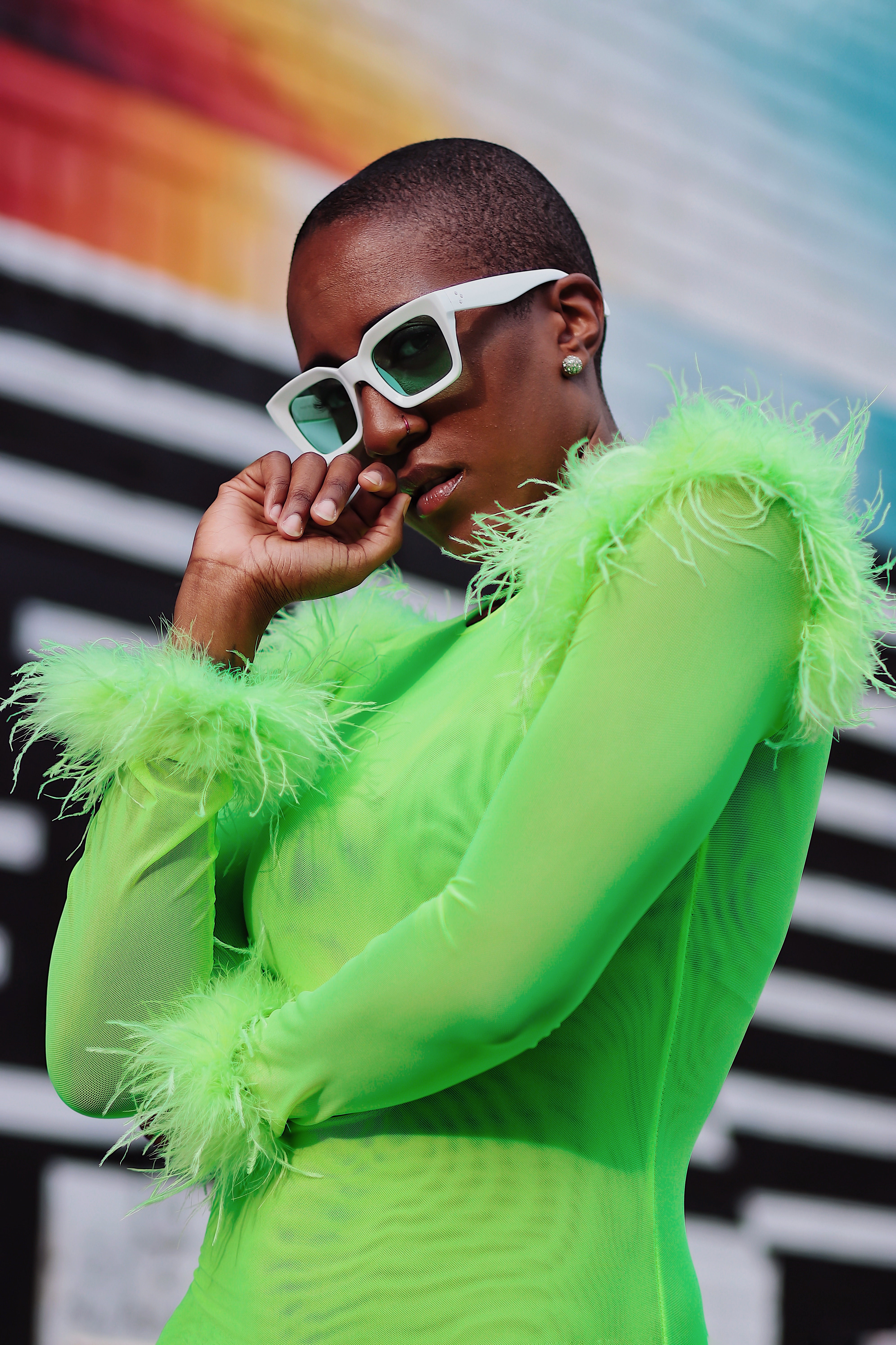fashion forward model wearing bright neon clothing against a n abstract background with colorfiul stripes and colors in new york new york