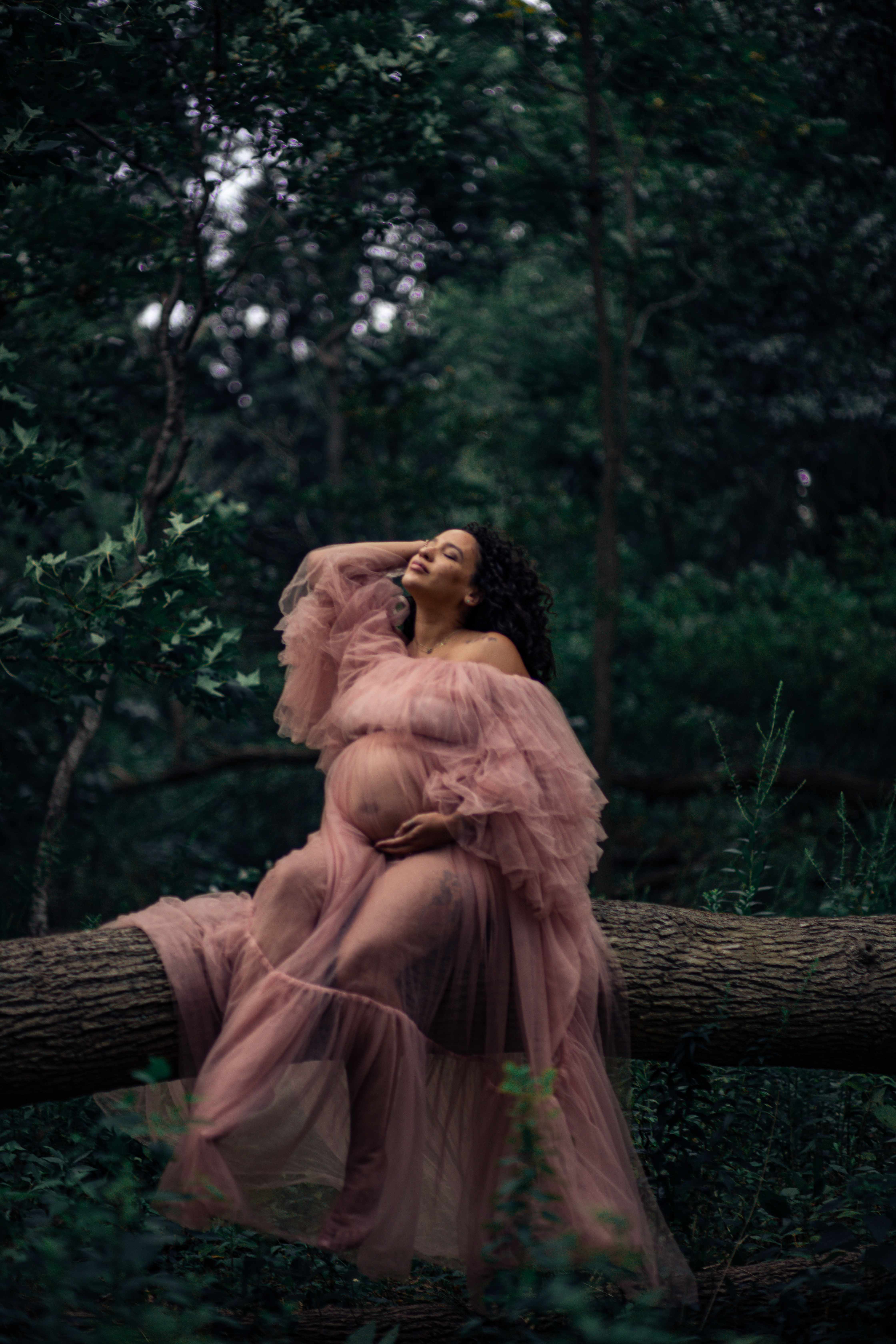 mom to be in nature, wearing a huge tulle gown while she embraces her baby bump