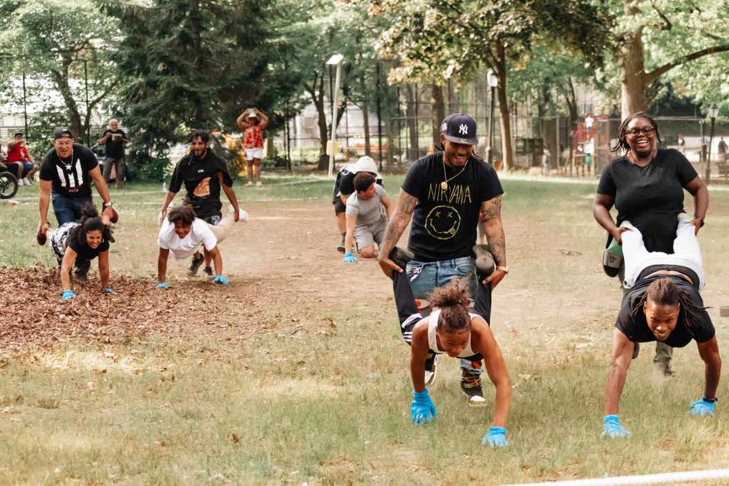 “These Field Day photos capture the energy, laughter, and unforgettable moments of a family tradition filled with games like tug-of-war, sack races, and wheelbarrow races. From candid smiles to action-packed shots, these images showcase the beauty of authentic, unposed photography. Perfect for celebrating family, fun, and life’s best memories.

Family in a park doing wheel barrow races 
