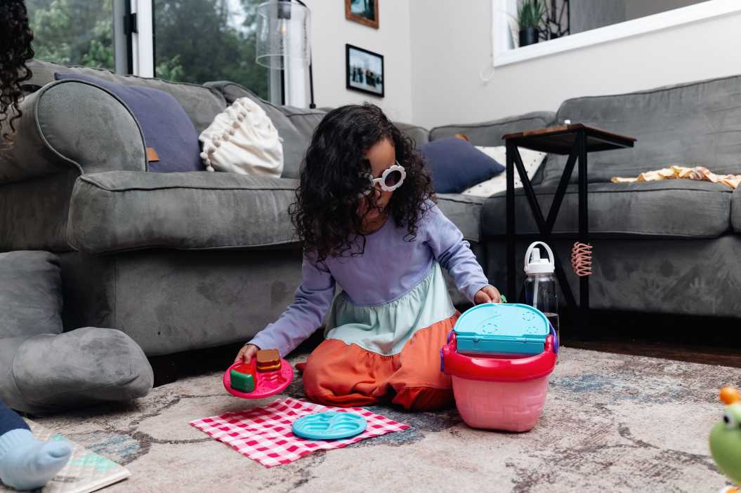three year old enjoying her playtime, being creative and using her imagination for playtime, while wearing some cool flower sunglasses