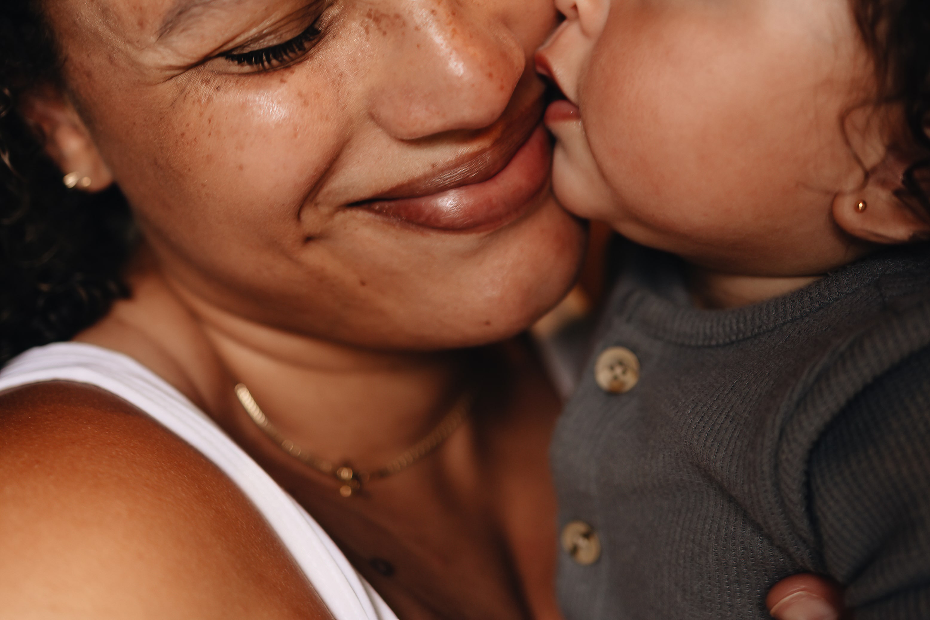 close up of mother and daughter snuggling, baby kisses mommy on the cheeck in trumbul ct