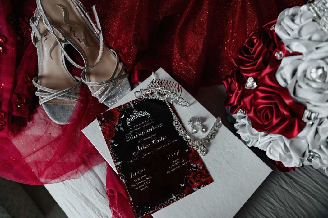 Quinceañera dressed in a red ball gown during her celebration at a VFW hall in Stratford, Connecticut, surrounded by elegant decor and traditional seating as she celebrates her fifteenth birthday, photographed in a documentary style to capture an authentic milestone event.
